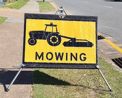 Multi Fit Roll Up Sign T1-Q10 Mowing Ahead sign mounted on a stand.