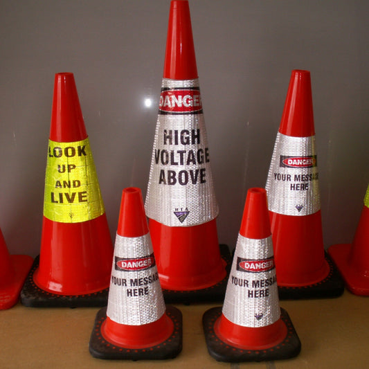 A set of red and white traffic safety cones with customizable printed warning labels, displayed on a brown surface against a gray background.