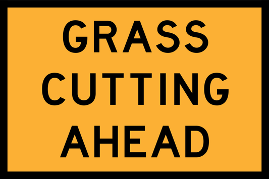 Warning sign with 'GRASS CUTTING AHEAD' text on a yellow background